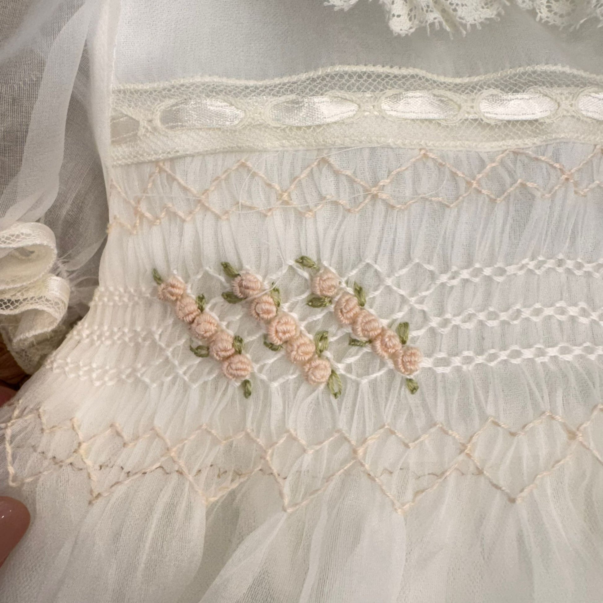 Dettaglio ricami artigianali floreali su abito battesimo bimba elegante
