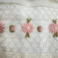 Dettaglio ricamo floreale rosa artigianale su abito battesimo bimba in organza di seta