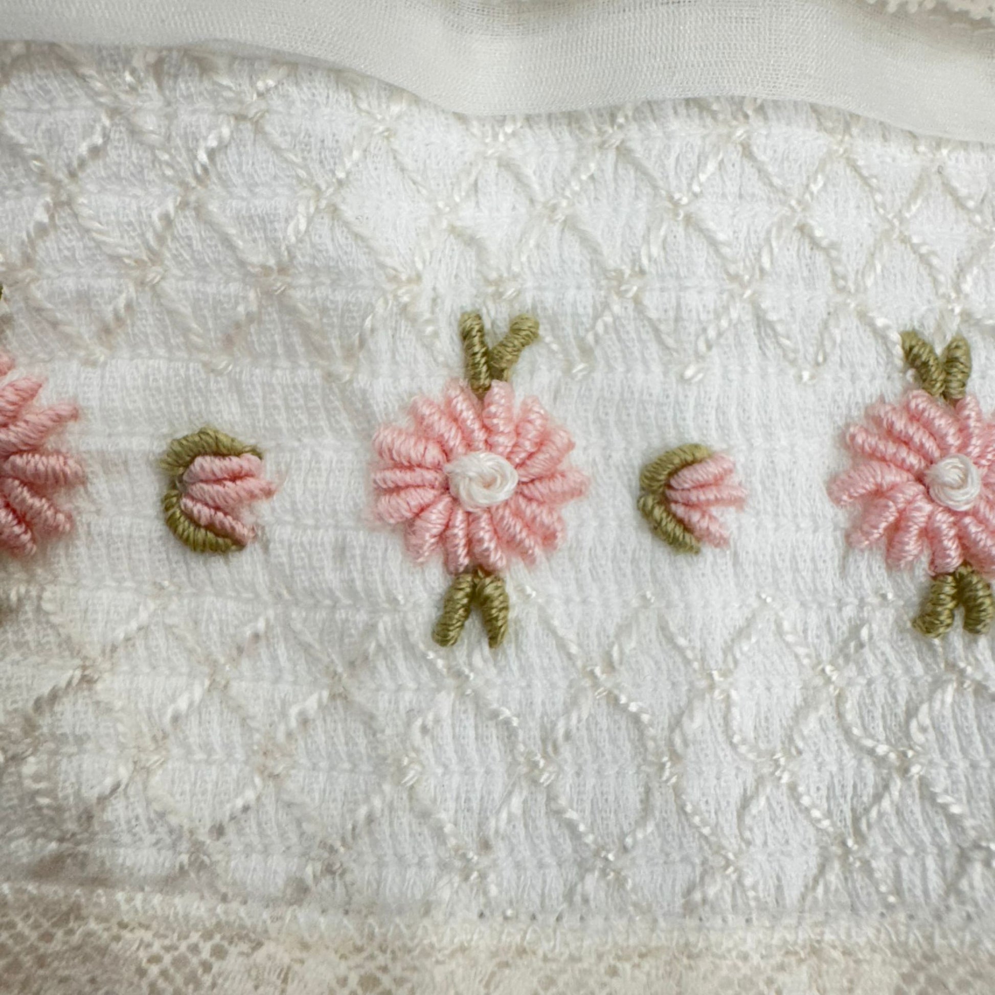 Dettaglio ricamo floreale rosa artigianale su abito battesimo bimba in organza di seta