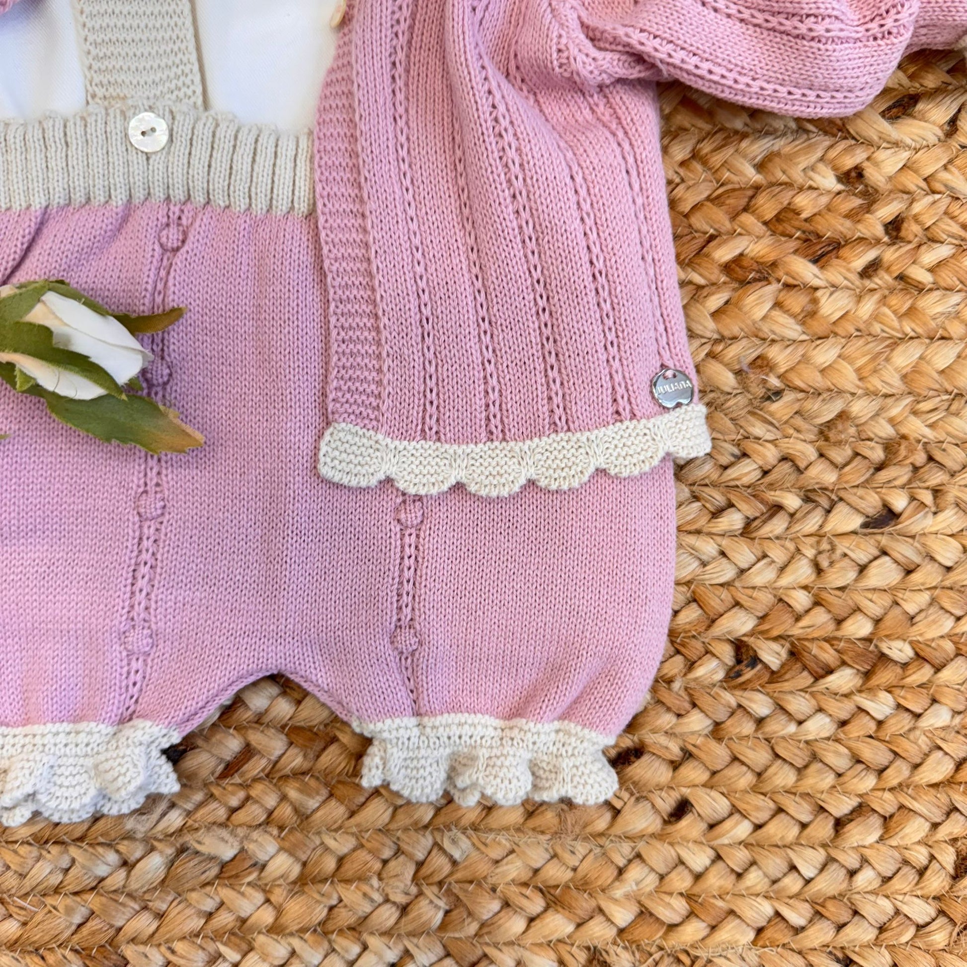 Particolare salopette rosa lavorata a maglia per neonato