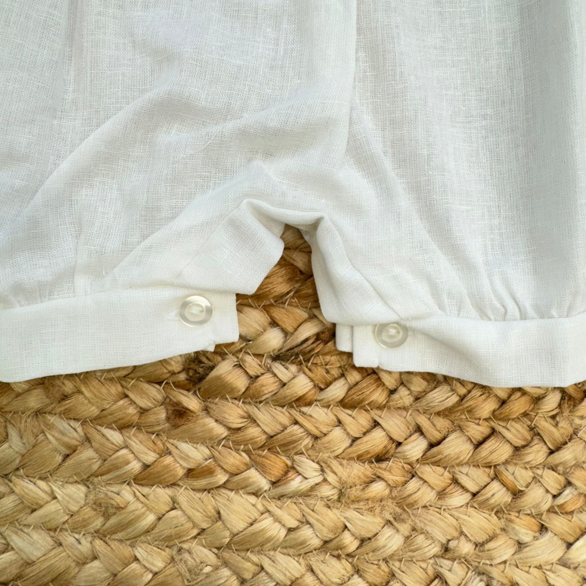 dettaglio bottoni e tessuto lino cotone pagliaccetto neonato