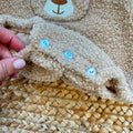 Dettaglio del tessuto teddy e dei bottoni del pagliaccetto neonato azzurro in caldo cotone.