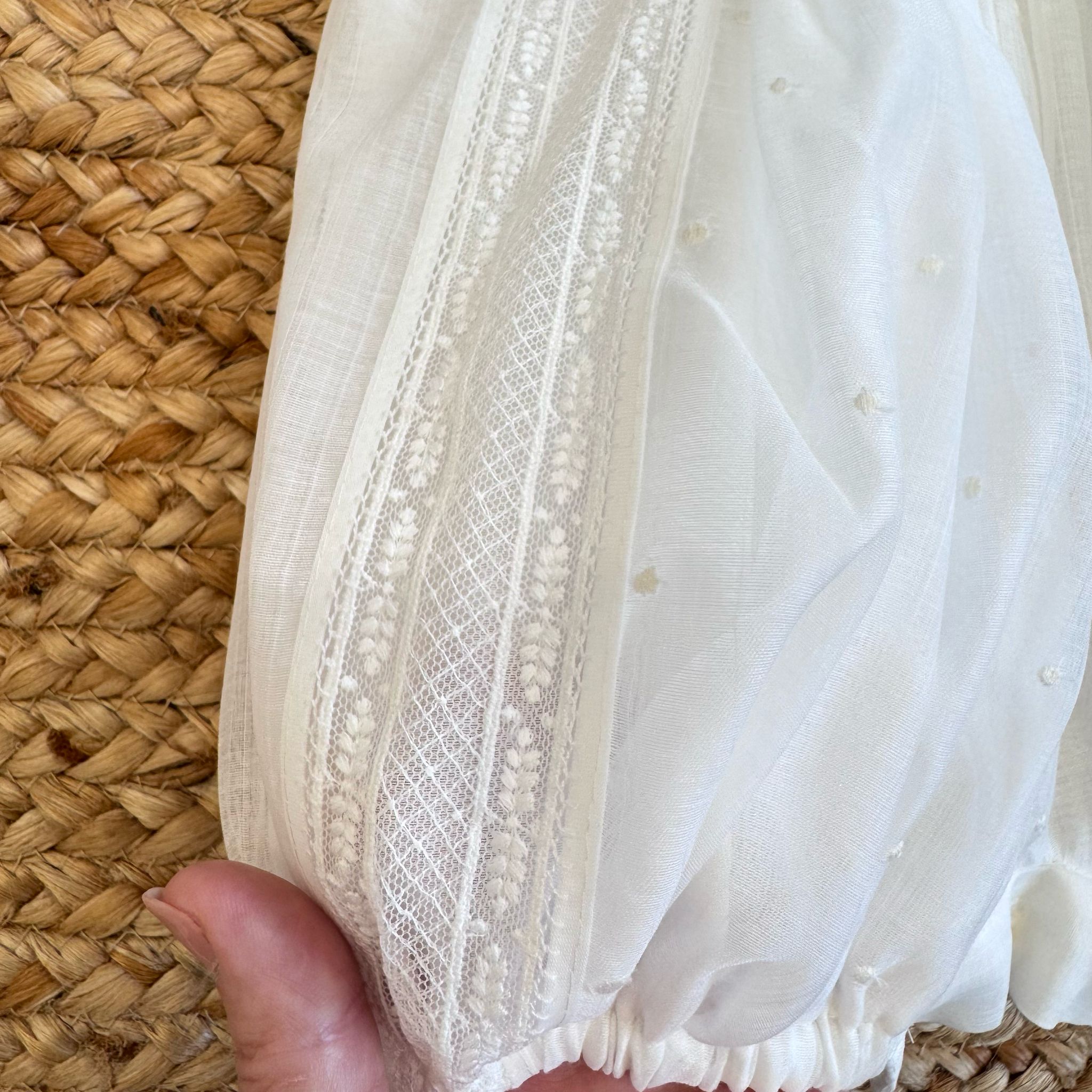 Inserti in pizzo e tulle con ricami su pagliaccetto neonato

