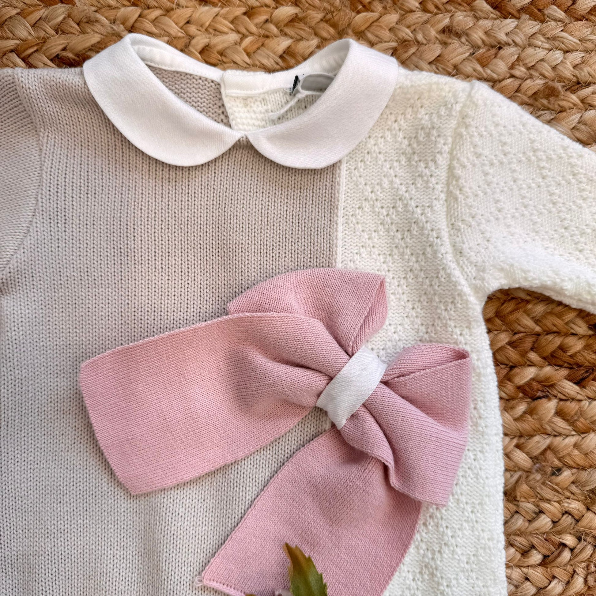 Colletto bianco e fiocco rosa su tutina bicolore in maglia per neonata