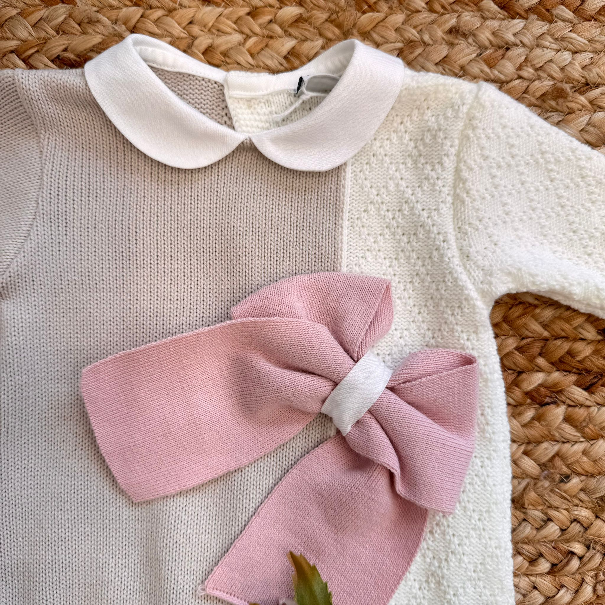 Colletto bianco e fiocco rosa su tutina bicolore in maglia per neonata