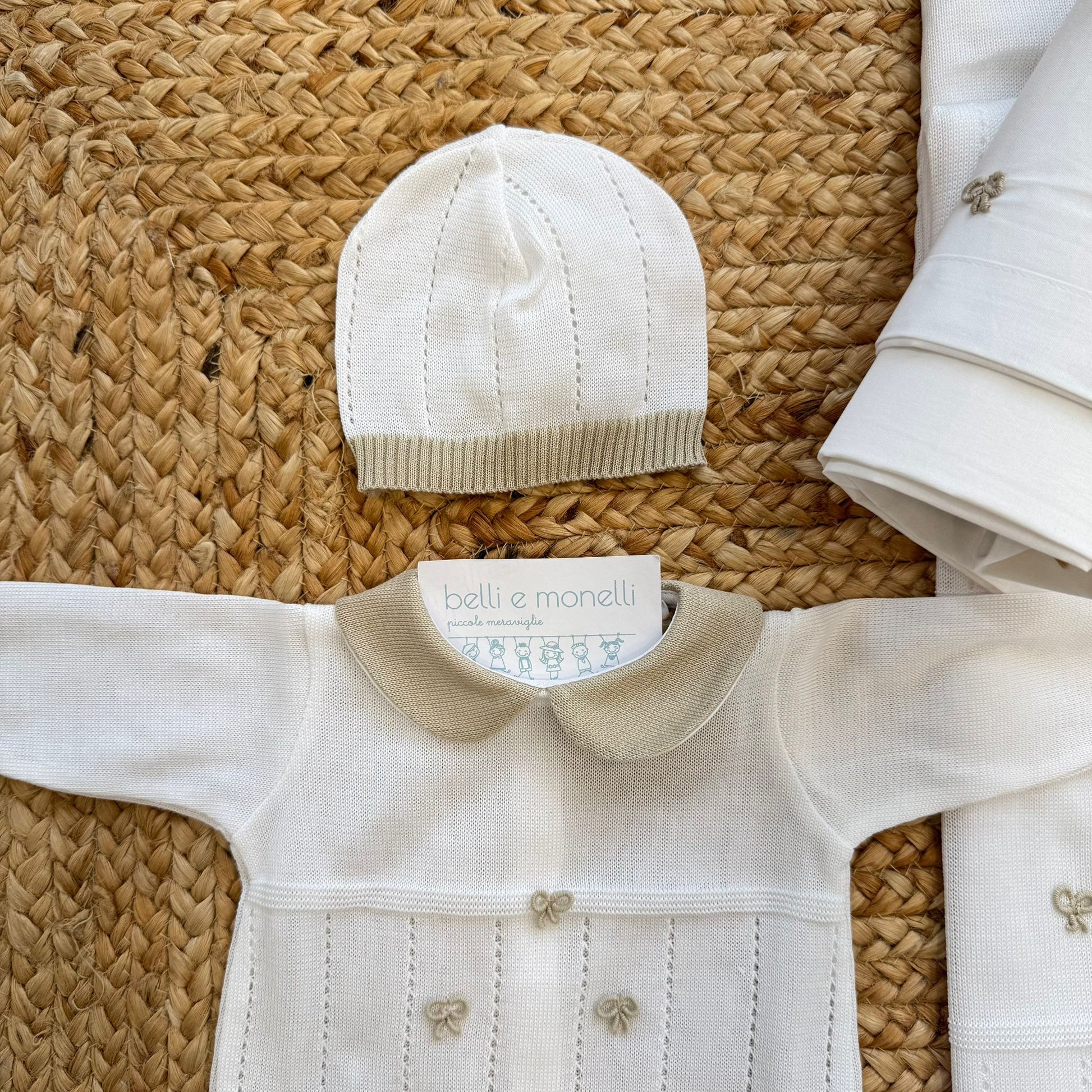 Dettaglio tutina con fiocchi applicati e colletto sabbia