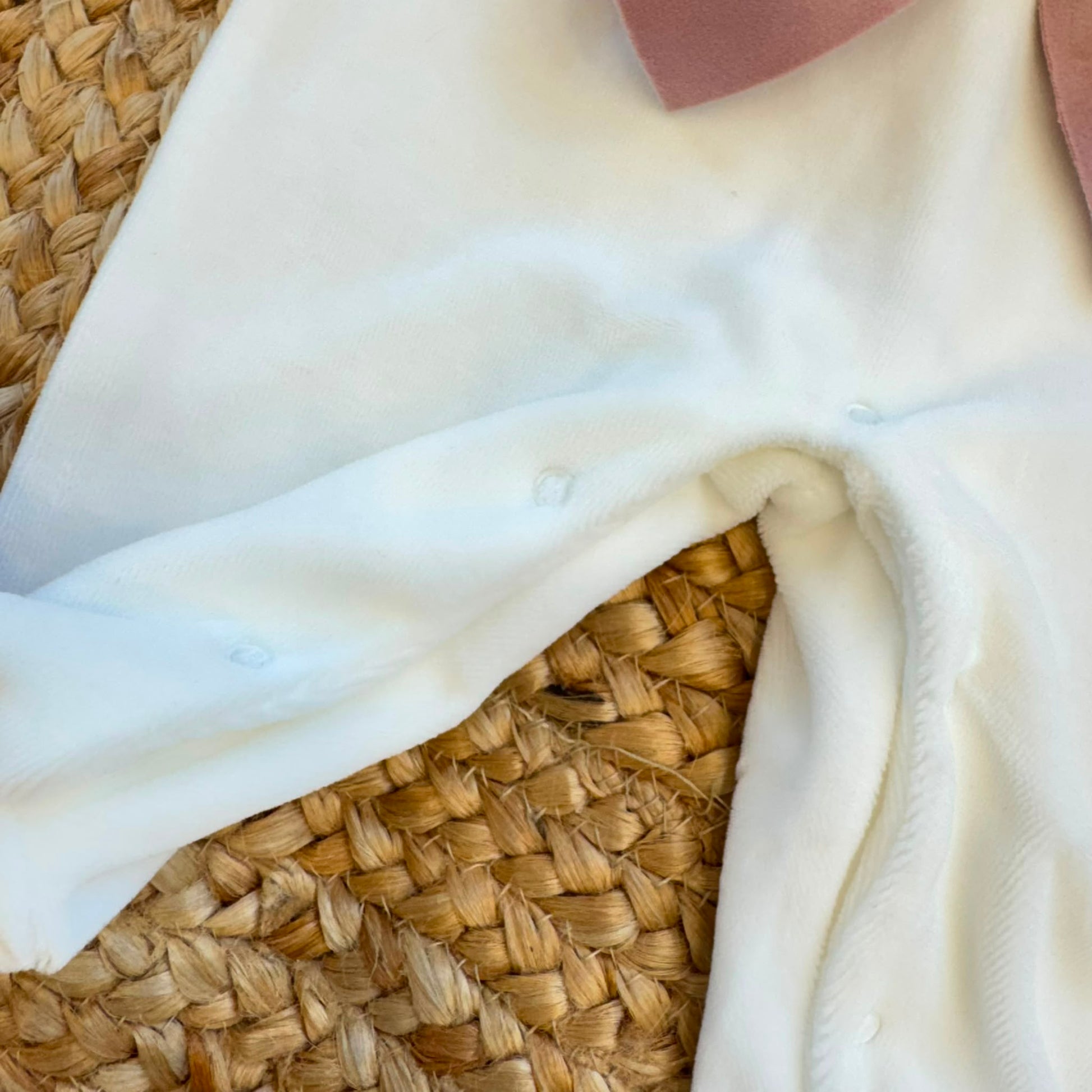 Uscita clinica neonata in ciniglia panna con ricamo floreale a cuore e fiocco rosa composta da tutina, bavetta, cappellino, lenzuola coordinate e copertina sfoderabile.