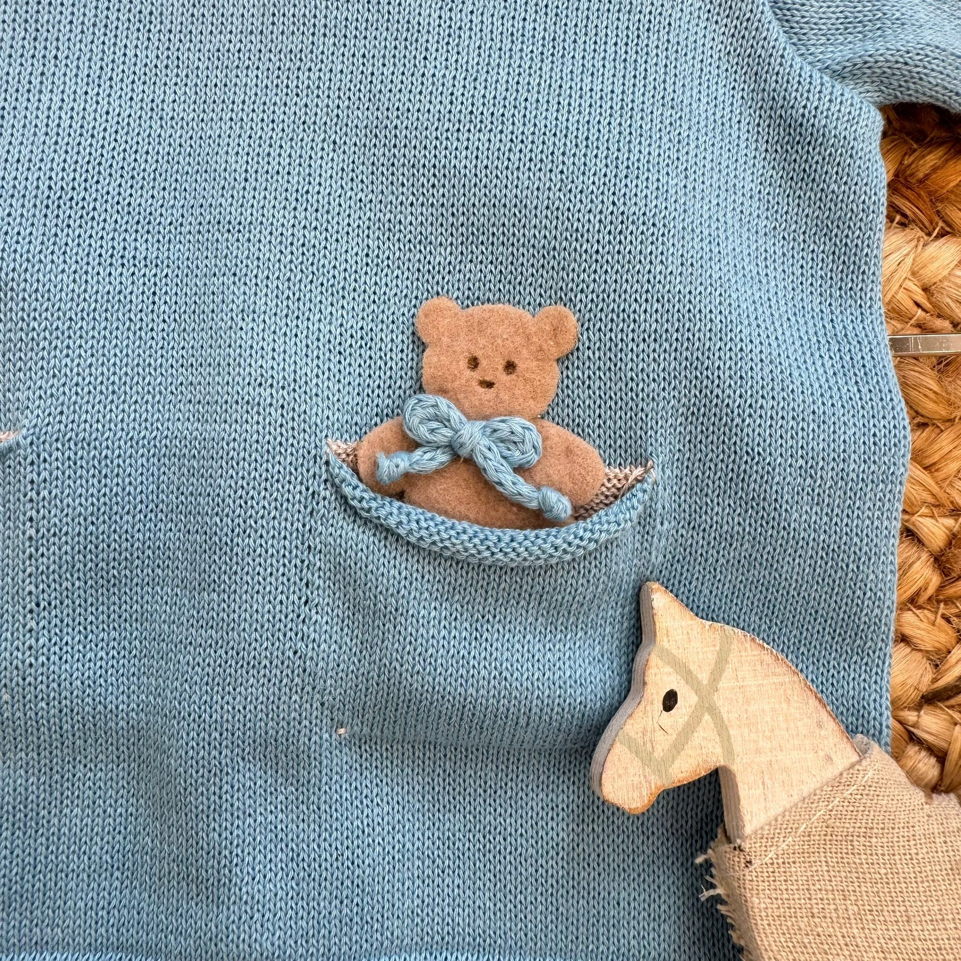 Dettaglio taschina con orsetto su tutina neonato in filo di cotone