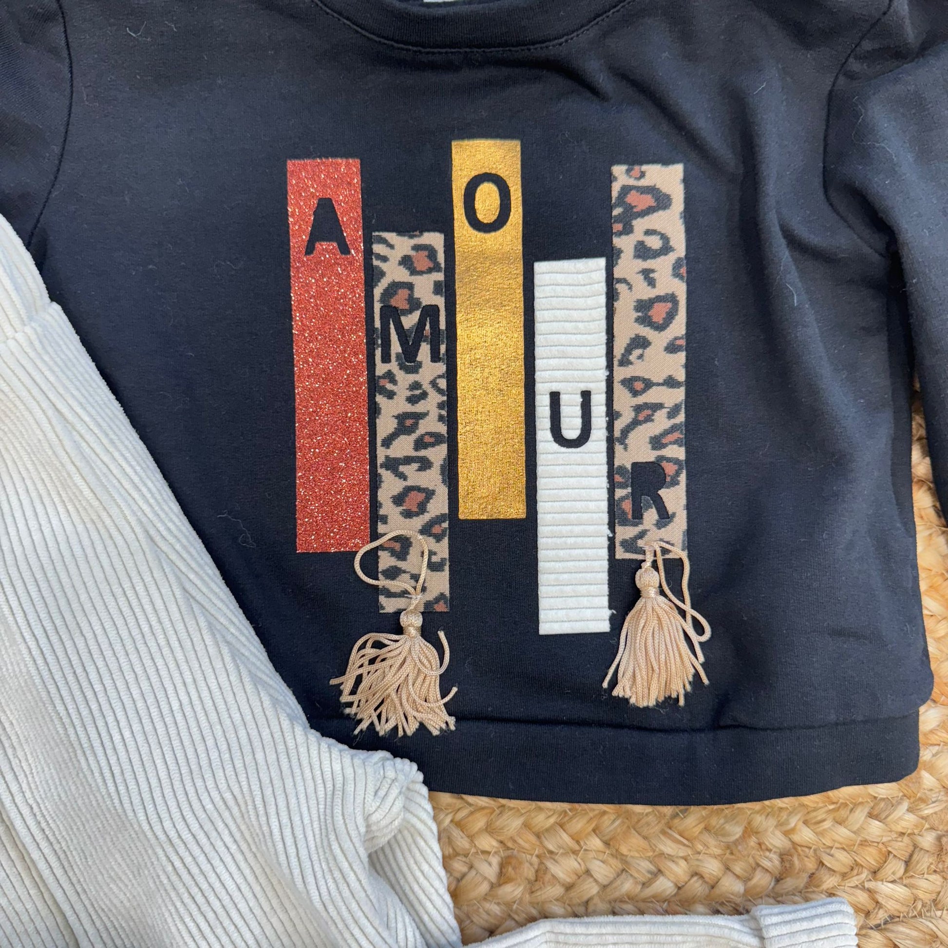 dettaglio felpa nera con scritta AMOUR glitter e animalier