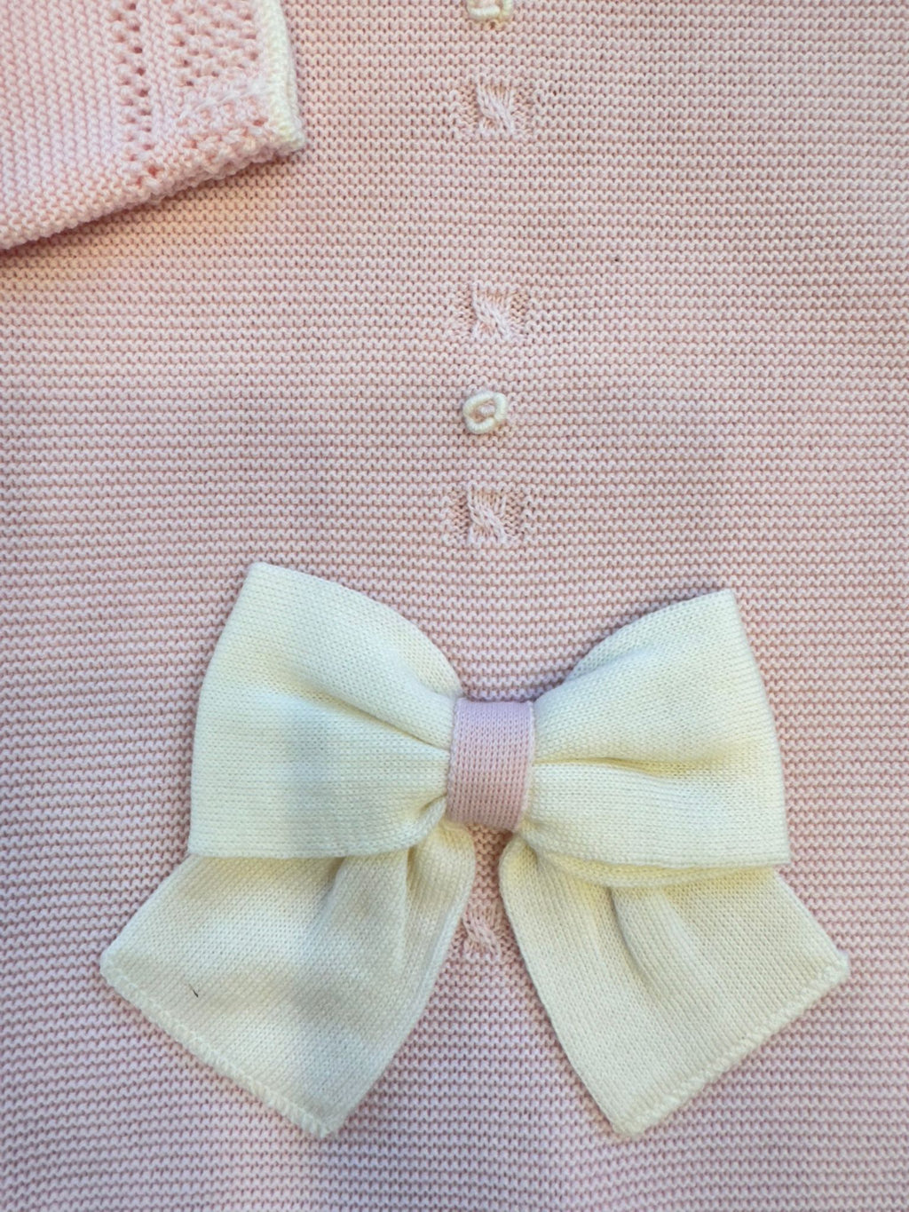 dettaglio fiocco panna su copertina rosa in lana