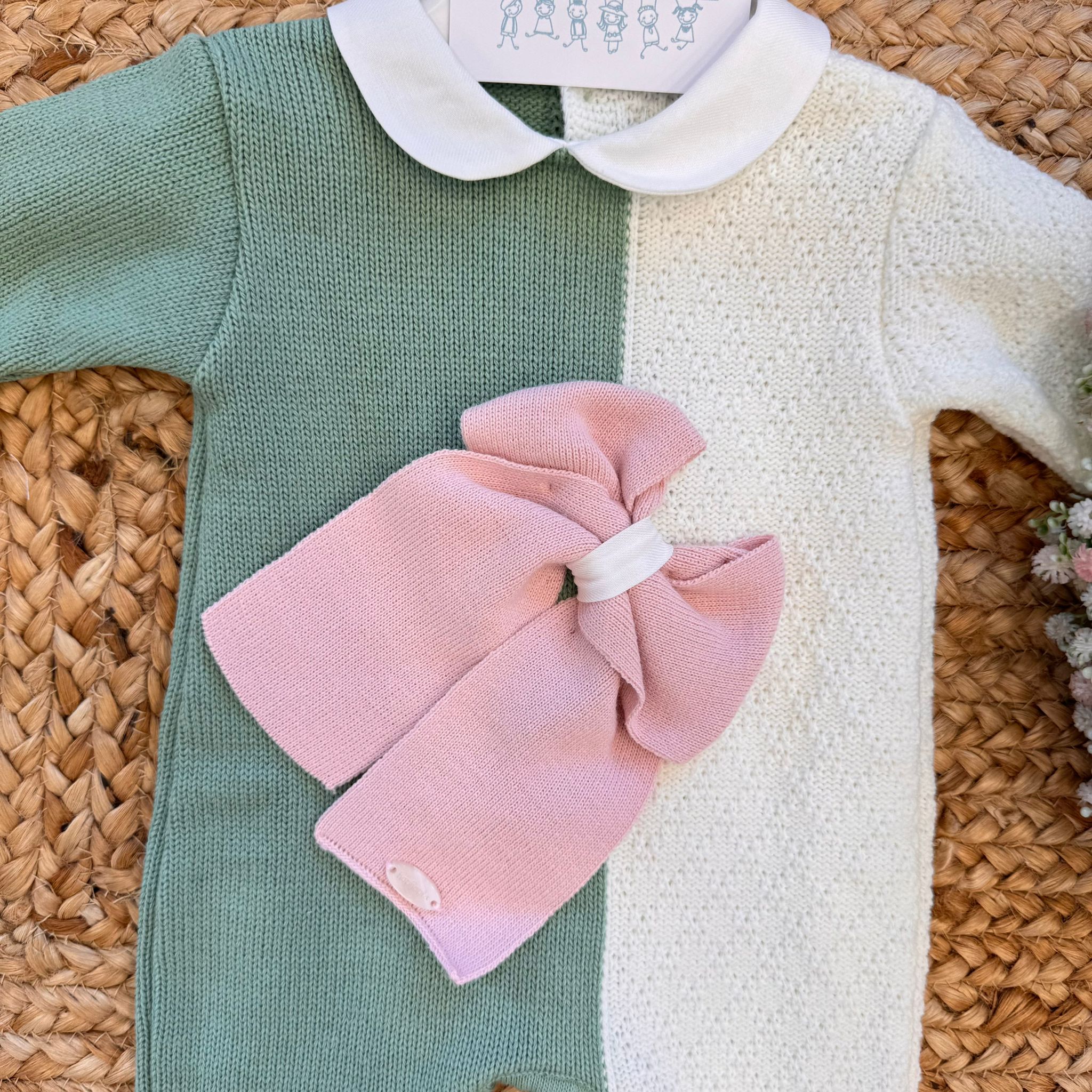 dettaglio maxi fiocco rosa su tutina verde e panna in misto lana