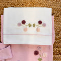 dettaglio ricamo fiori su maglia e copertina neonata