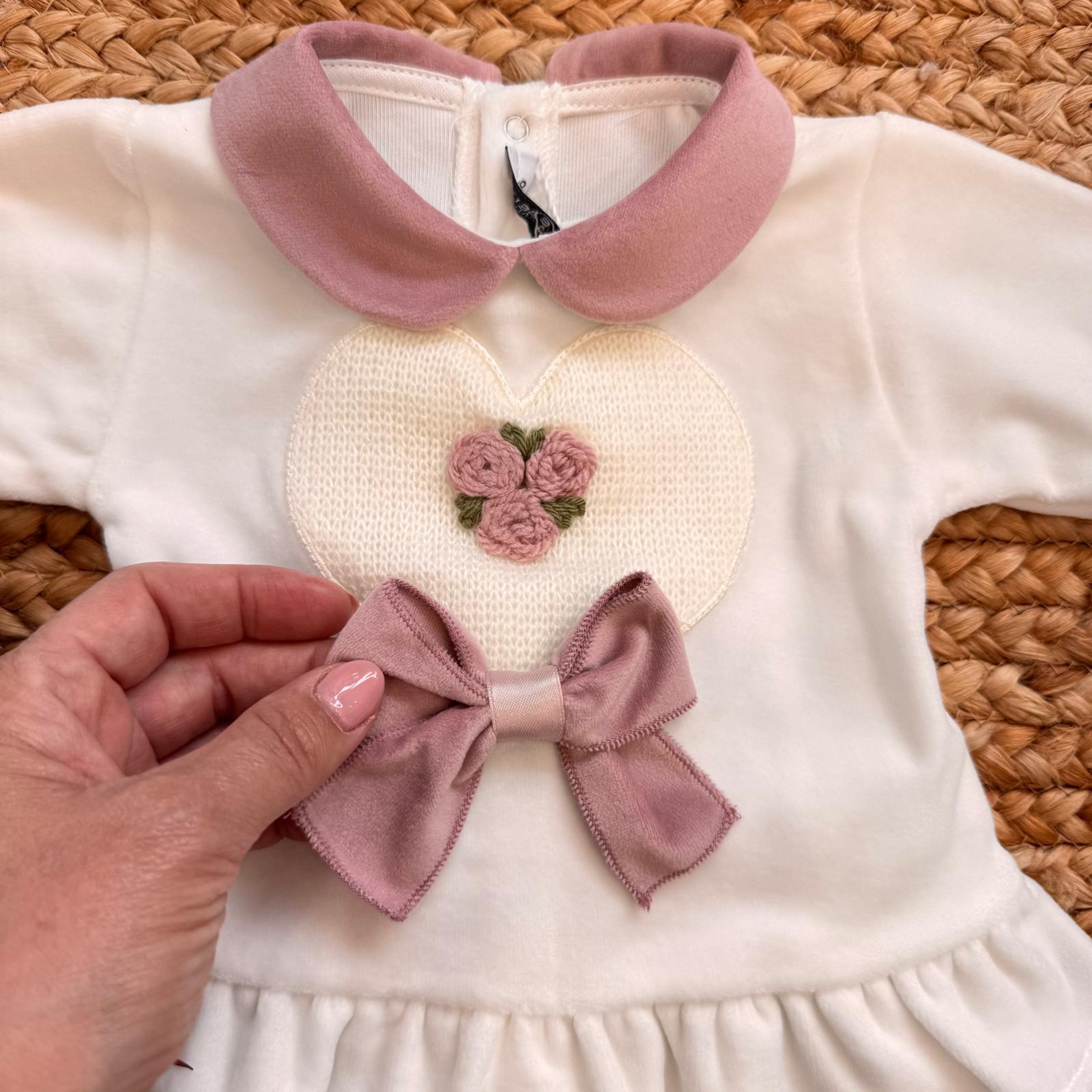 dettaglio ricamo floreale e fiocco rosa cipria sulla tutina neonato