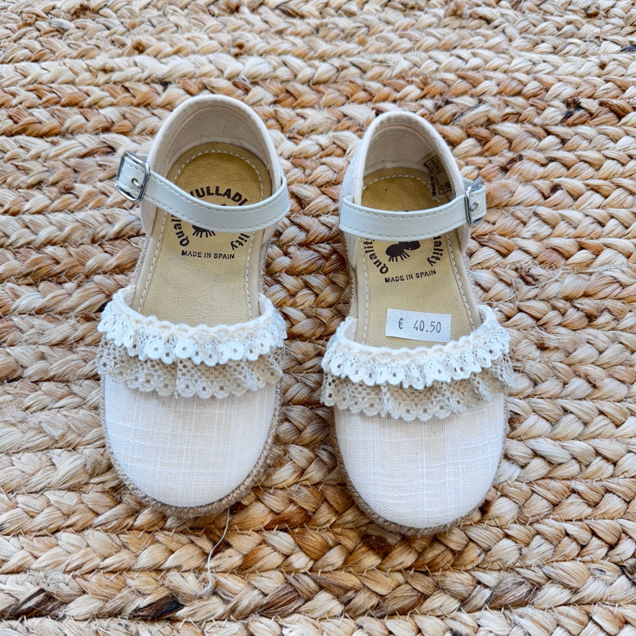 Espadrillas avorio per bambina con merletto delicato, suola in corda e cinturino alla caviglia per un tocco di eleganza.