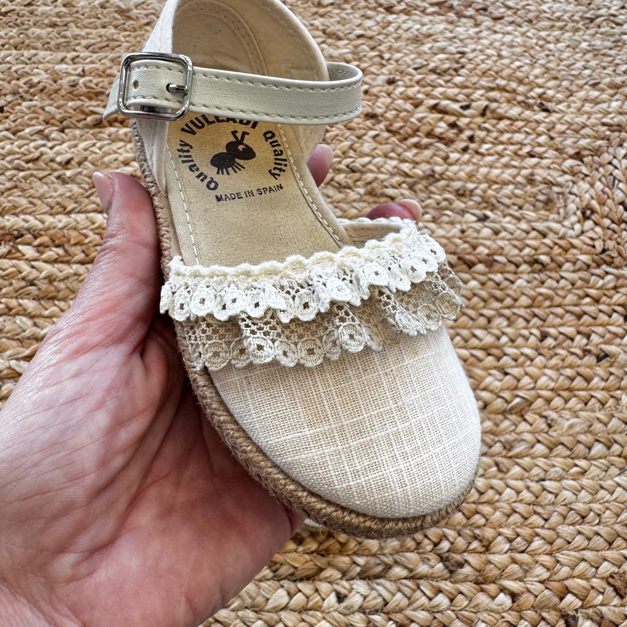 Espadrillas eleganti in tessuto avorio con dettagli in pizzo e suola in juta intrecciata, ideali per look raffinati.