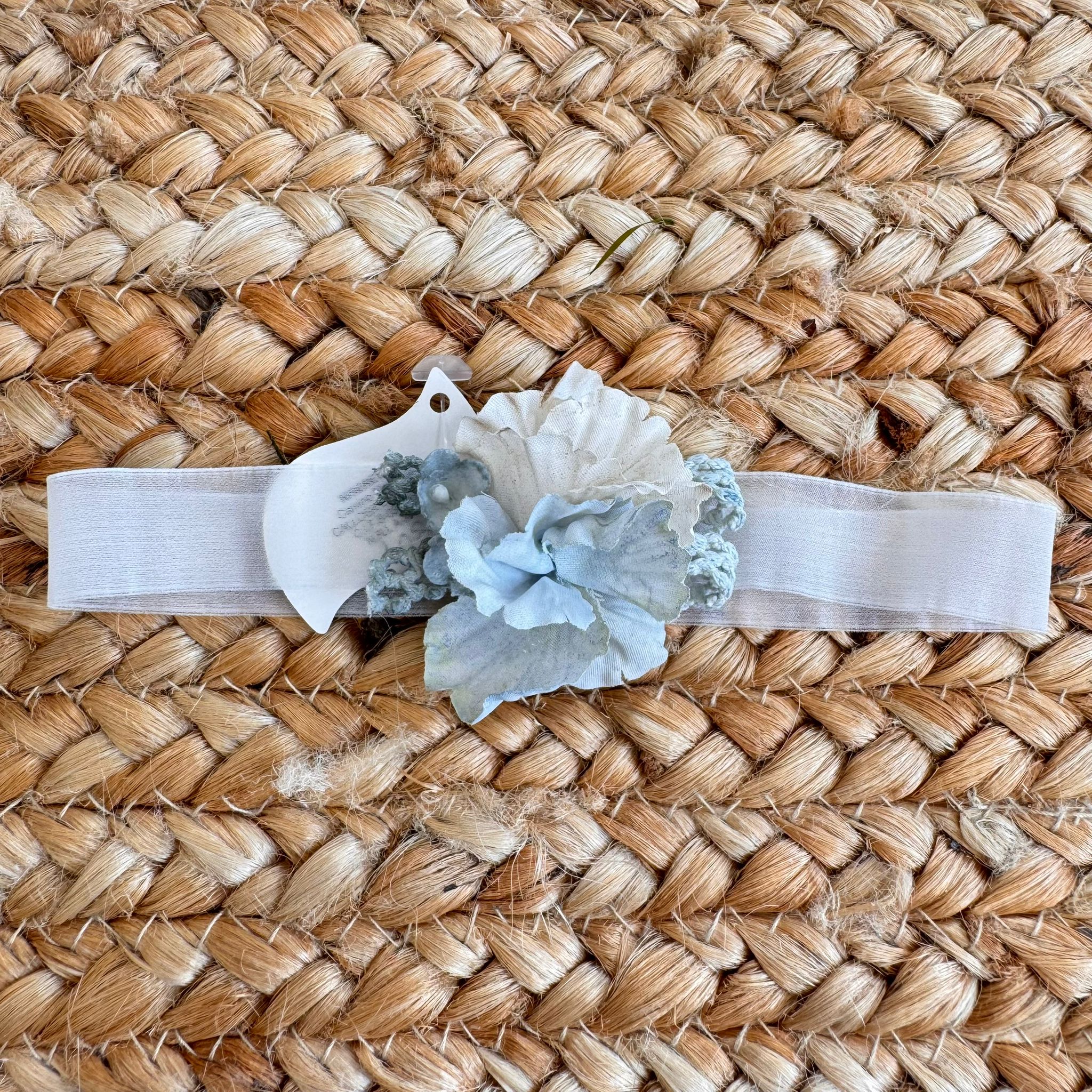 Fascetta battesimo bambina con fiori azzurri su nastro elastico bianco
