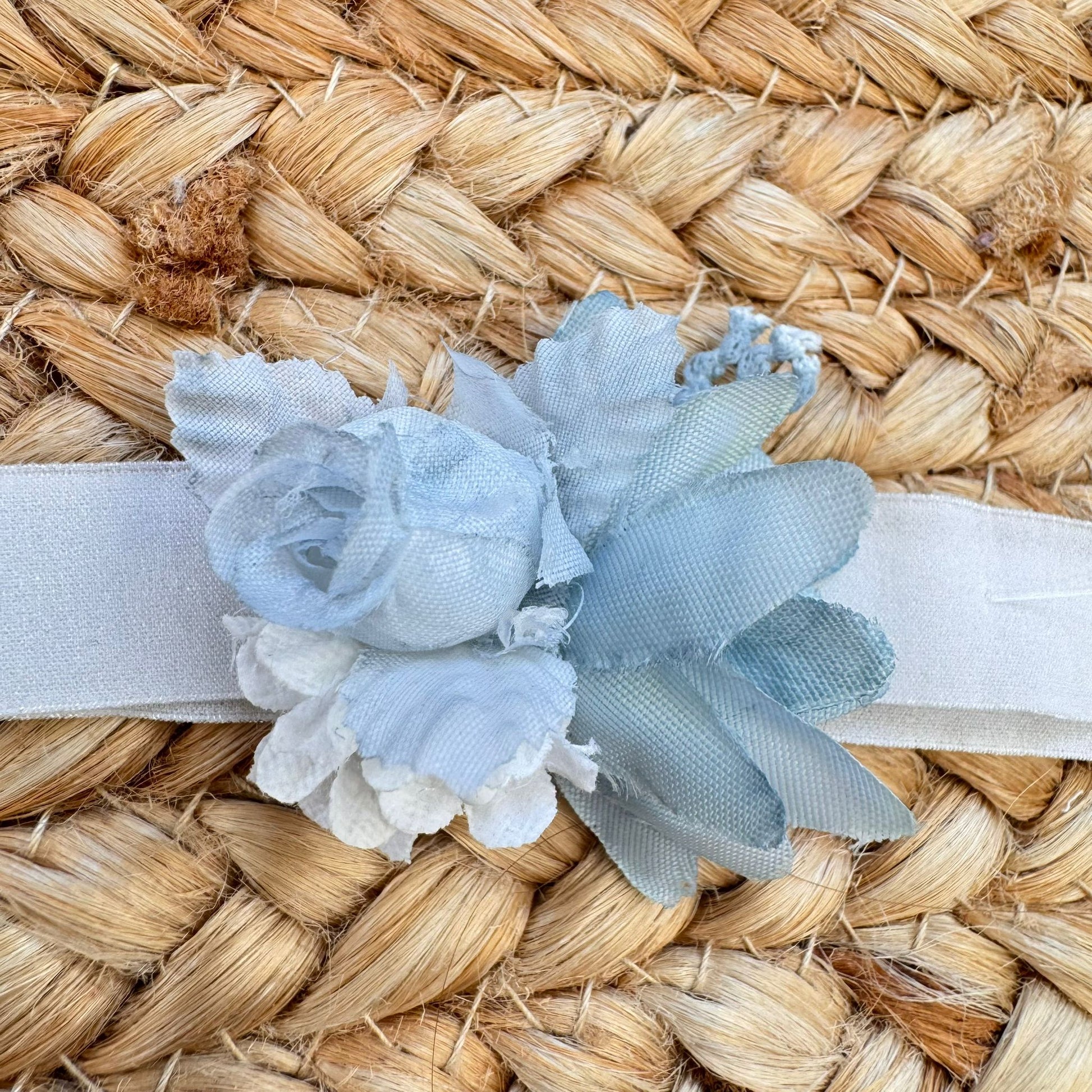 Dettaglio fascia cerimonia bimba con applicazione floreale azzurro polvere