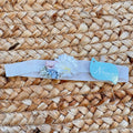 fascia battesimo bimba con fiore decorativo bianco e dettagli rosa e azzurro