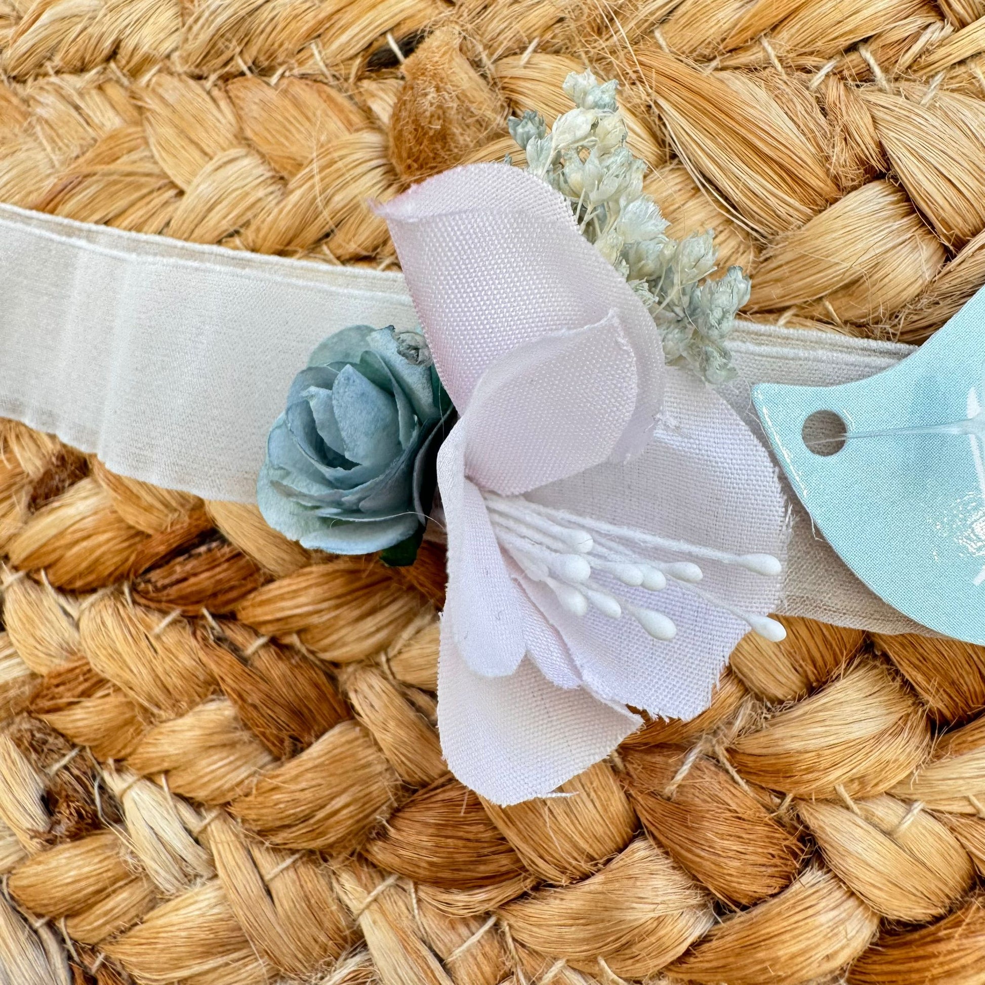 Dettaglio fascia cerimonia bimba con applicazione floreale azzurra e cipria