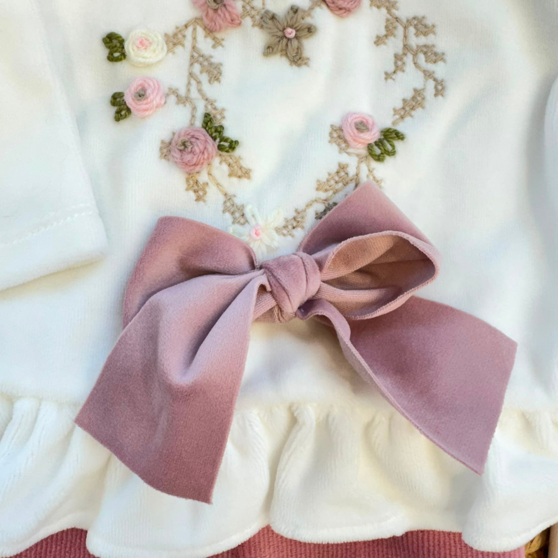Uscita clinica neonata in ciniglia bianca e rosa con completino ricamato a cuore floreale, fiocco applicato, cappello, bavetta, scarpine, lenzuola coordinate e copertina sfoderabile.