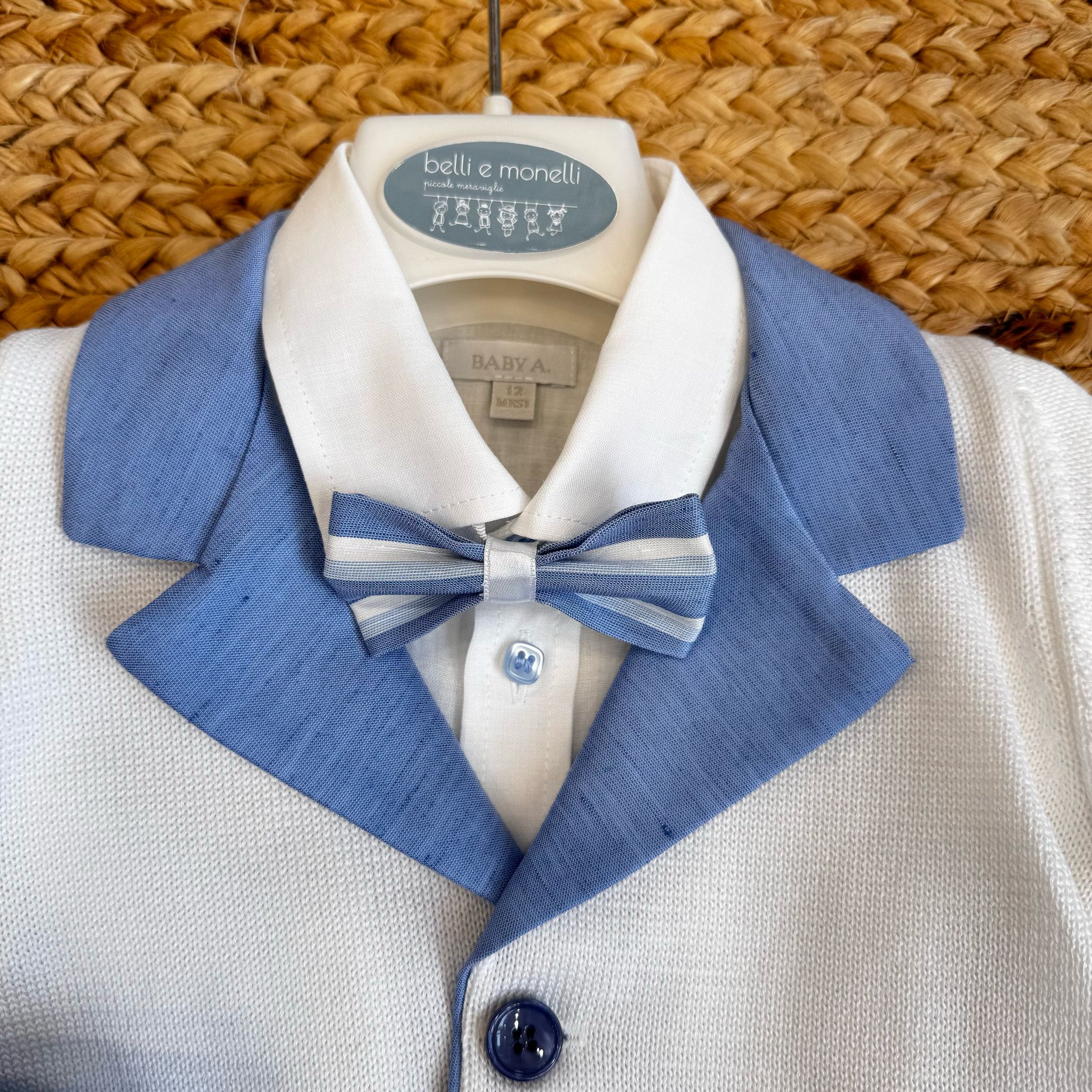 Dettaglio giacca in filo bianca con rever azzurro e papillon coordinato.