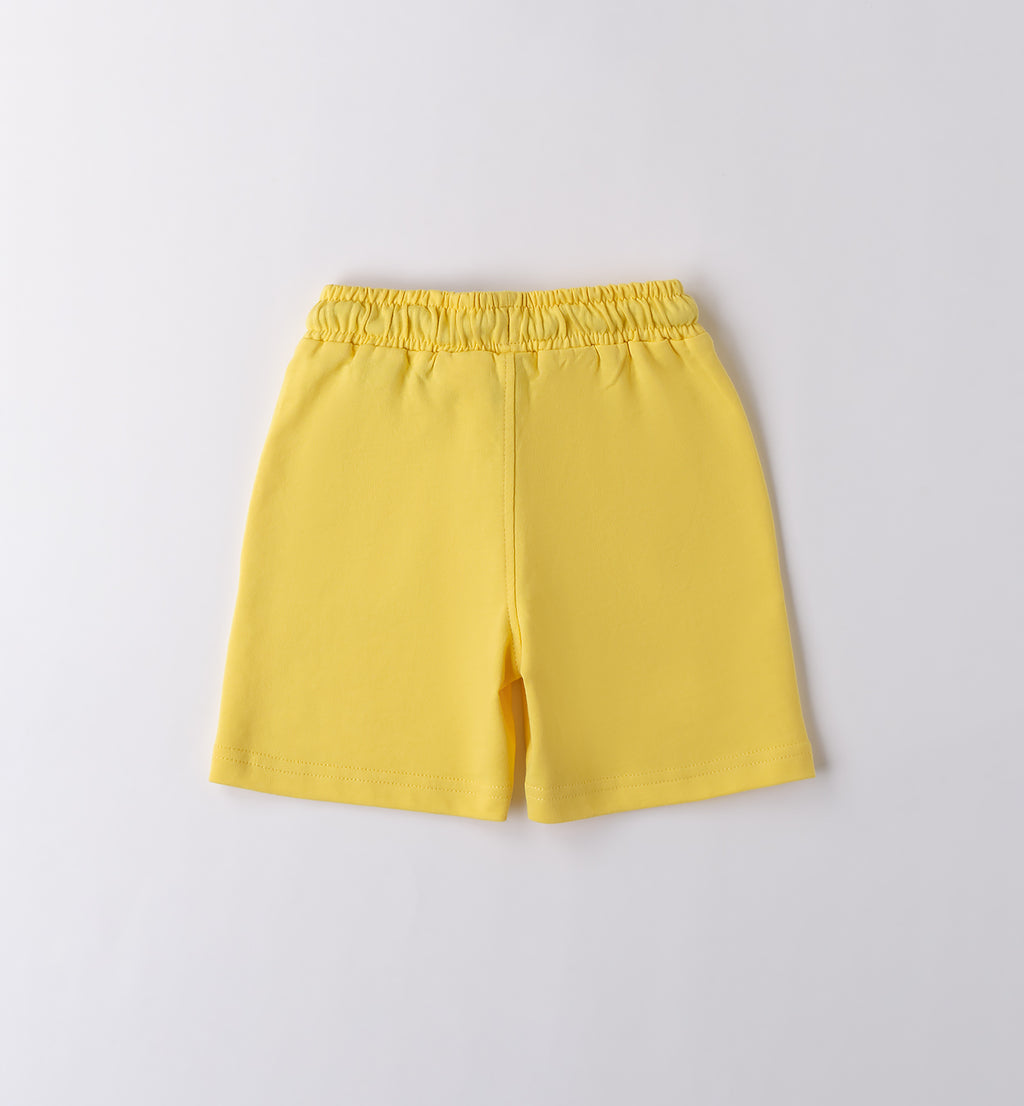 T-shirt bianca con stampa tropicale e pantaloncini gialli per bambino, abbigliamento estivo vivace.