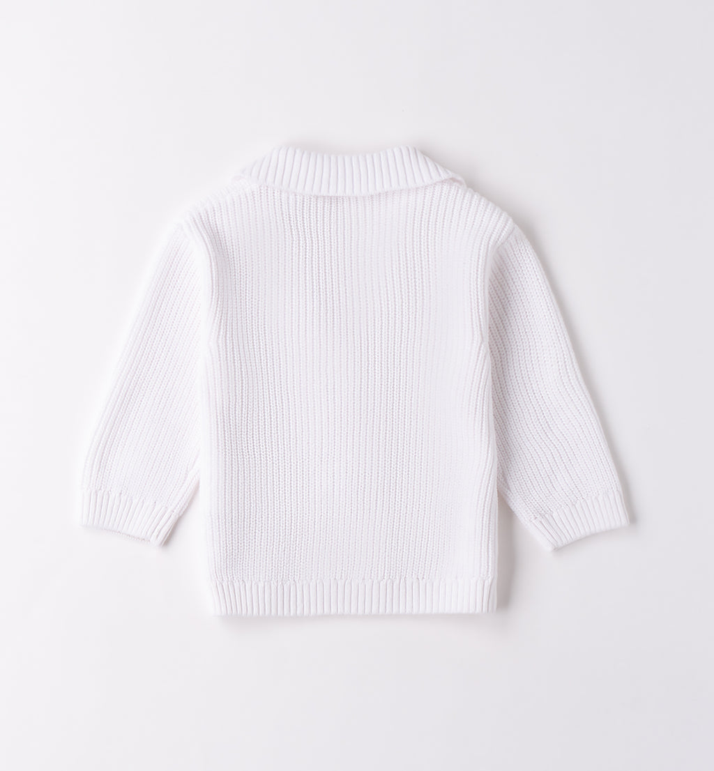 maglione bianco con camicia blu e pantaloni beige per bambino, con dettagli in blu e camicia azzurra in lino. perfetto per un look elegante e casual.