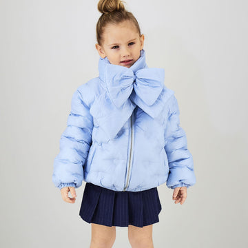 Bambina con giubbotto celeste imbottito e sciarpa coordinata con maxi fiocco