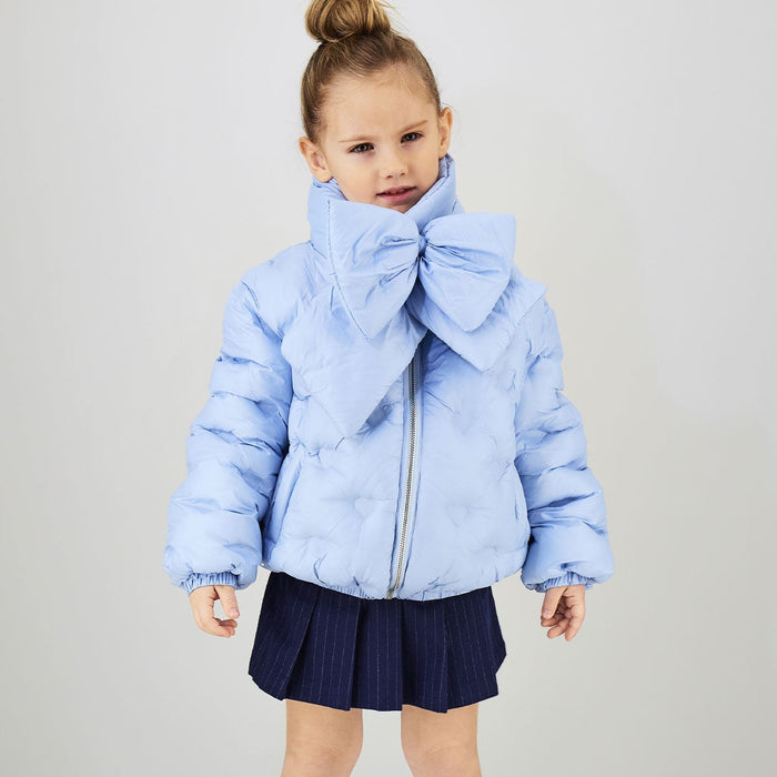 Bambina con giubbotto celeste imbottito e sciarpa coordinata con maxi fiocco