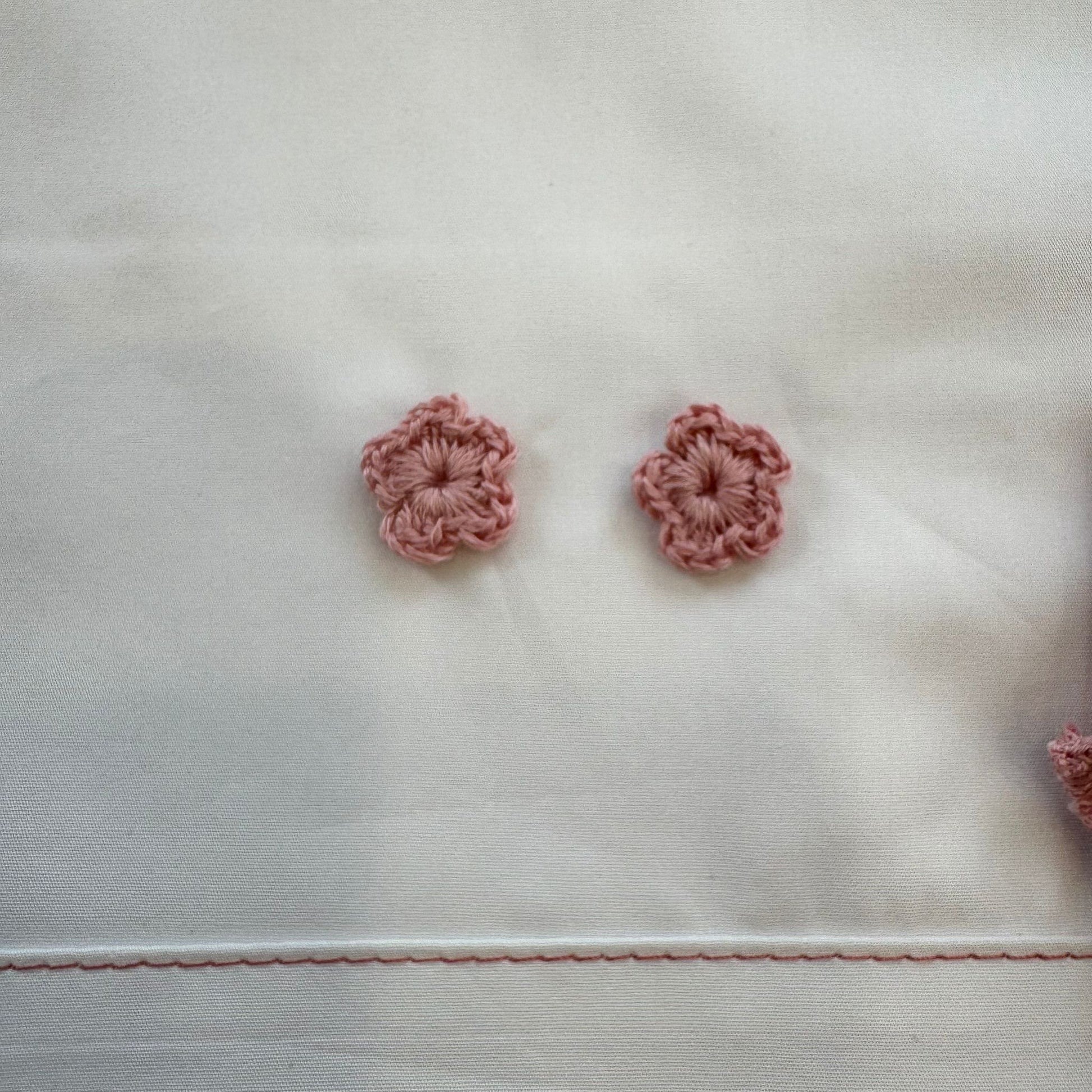 Dettaglio fiori crochet rosa cipria applicati su lenzuola neonata in cotone