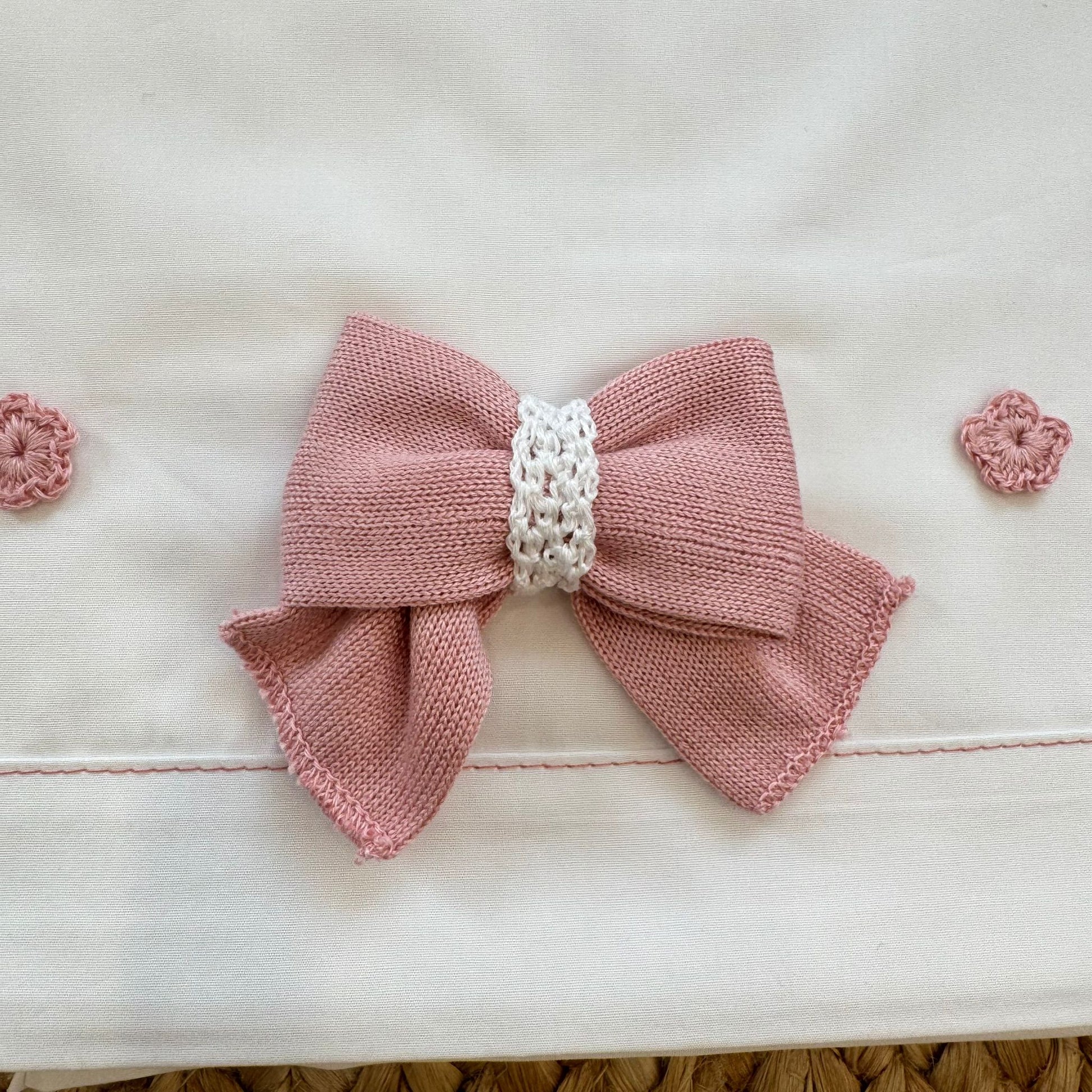 Dettaglio fiori crochet rosa cipria applicati su lenzuola neonata in cotone