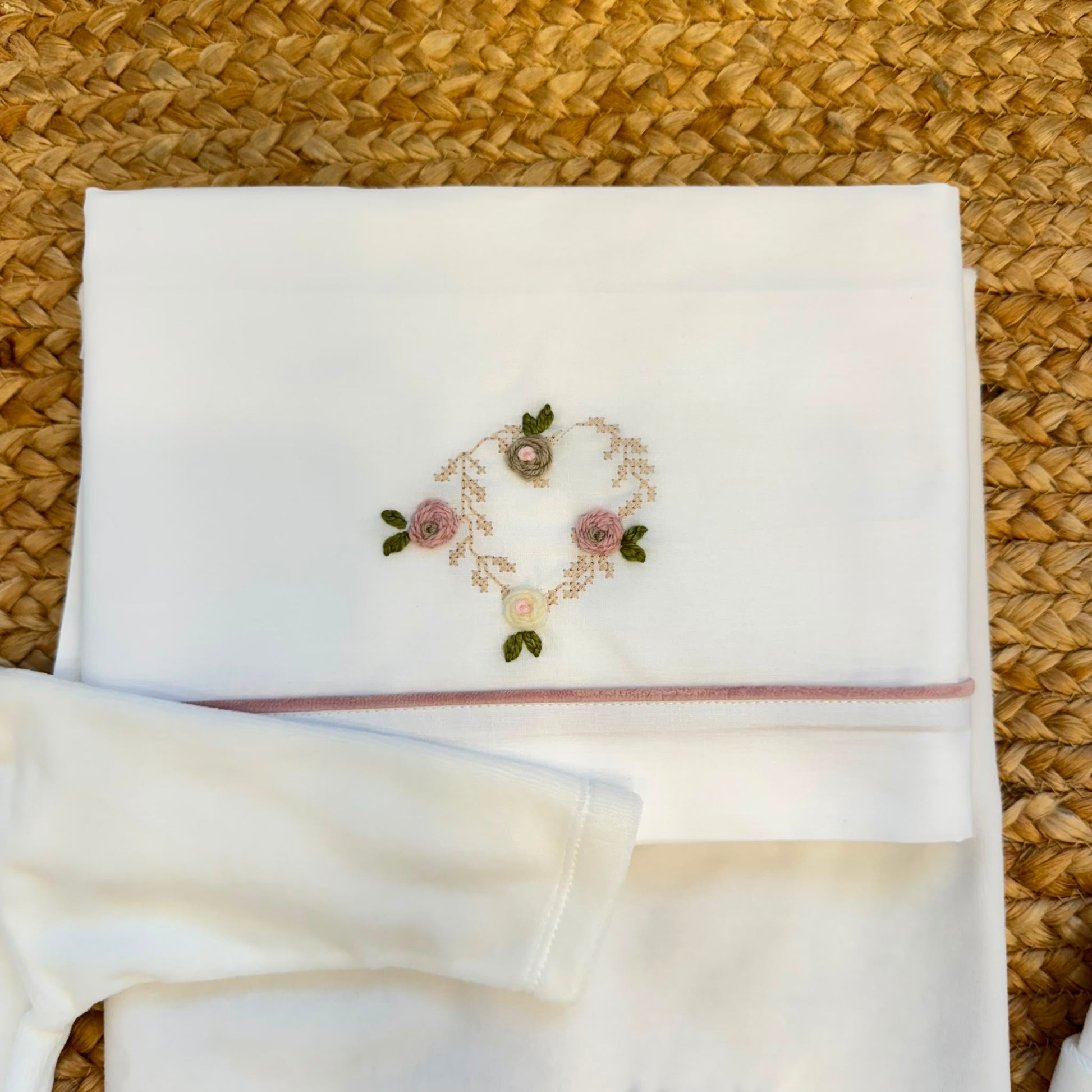 Uscita clinica neonata in ciniglia bianca e rosa con completino ricamato a cuore floreale, fiocco applicato, cappello, bavetta, scarpine, lenzuola coordinate e copertina sfoderabile.