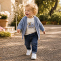 Bambino con cardigan celeste, maglia bianca con orsetti e jeans blu