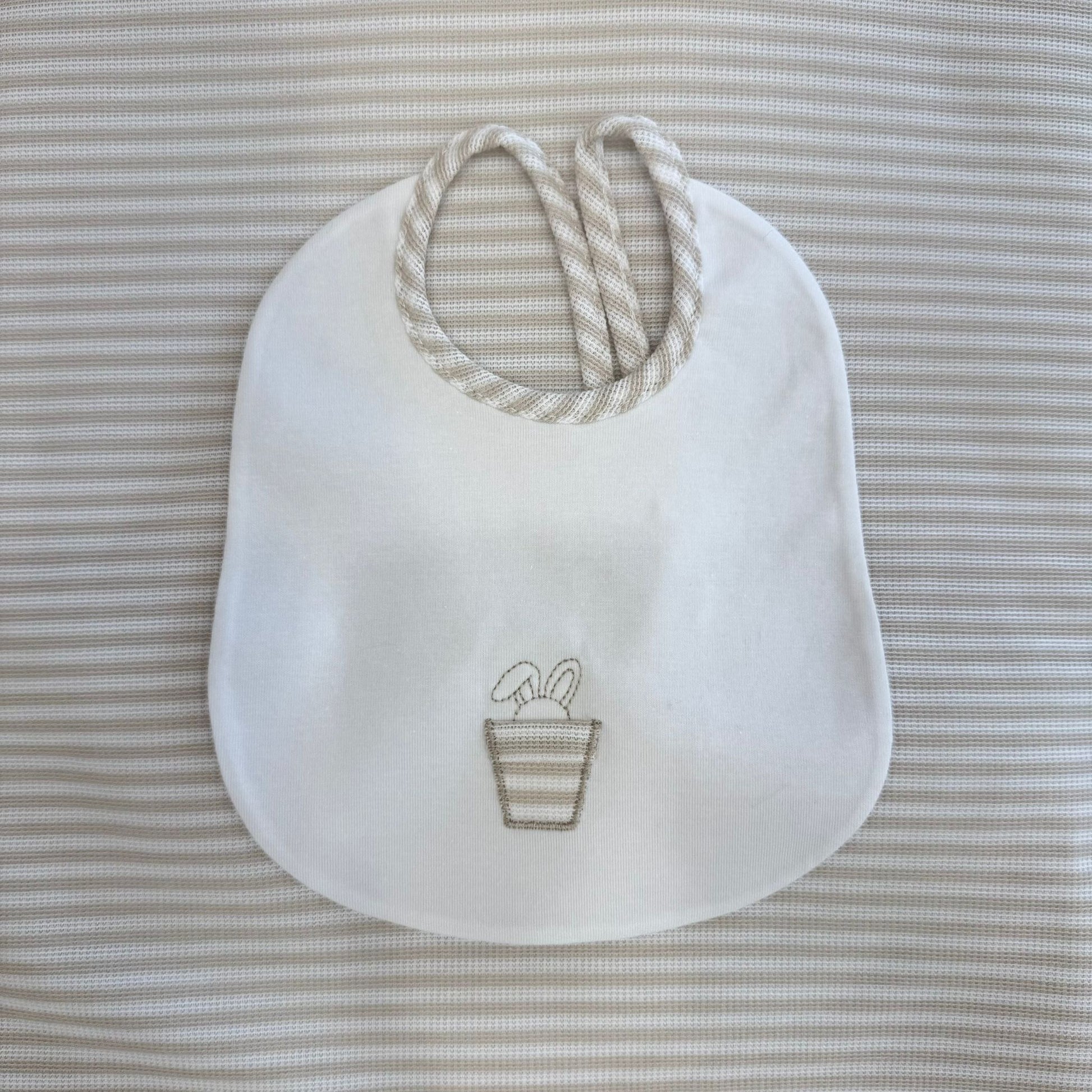 Dettaglio applicazioni in tessuto coniglietti su maglietta per neonato in cotone bianco con colletto rigato.