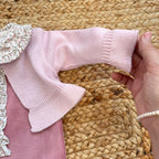 Primo piano manica cardigan rosa cipria abbinato alla tutina – corredino neonata inverno