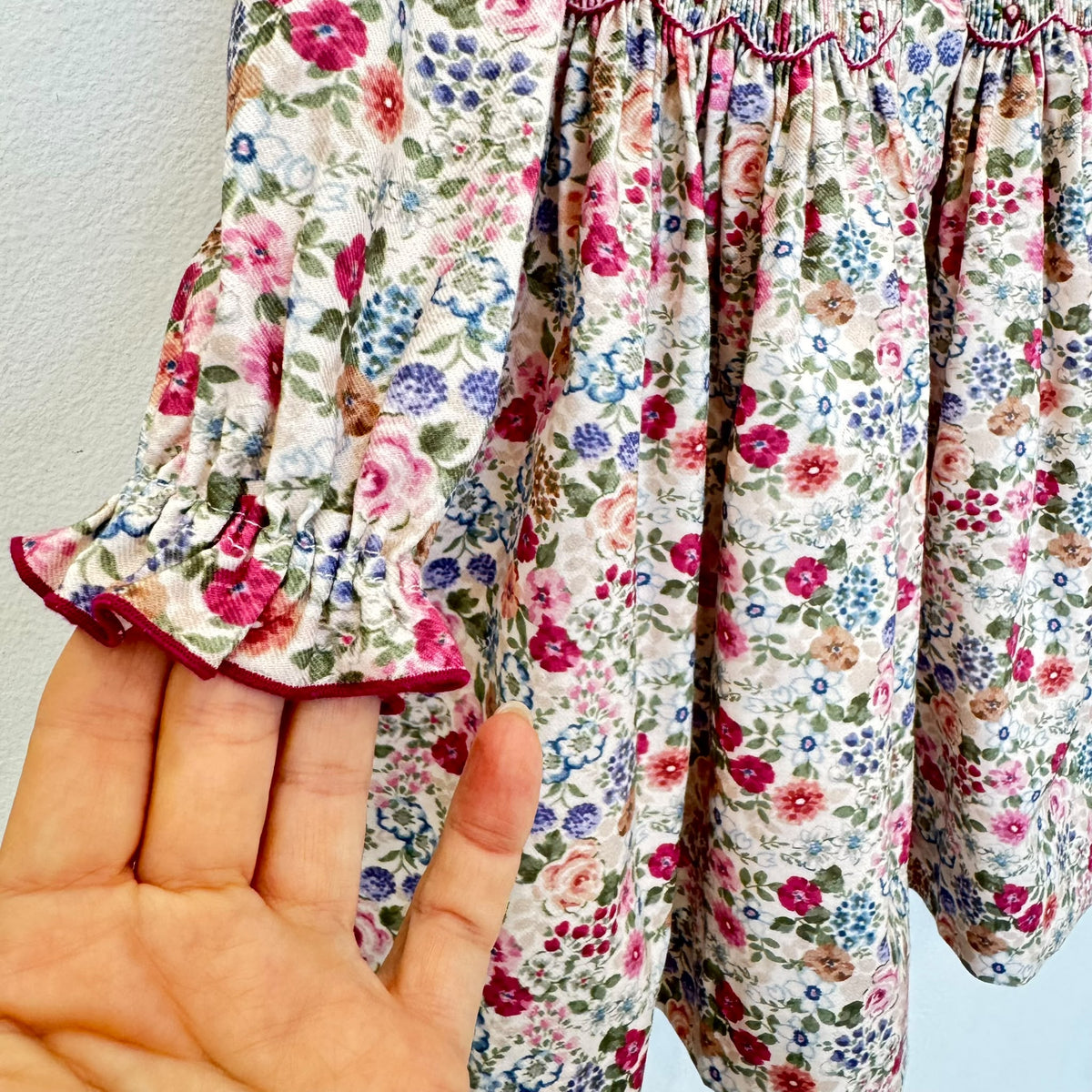 Abito bambina floreale in cotone con punto smock, colletto arricciato e dettagli bordeaux Kidivi.