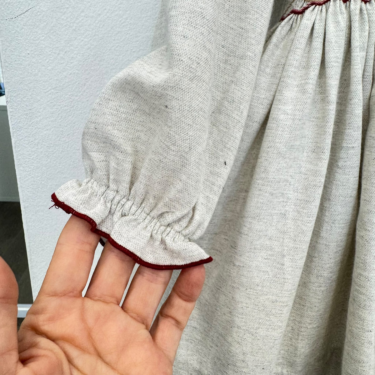 Abito bimba grigio chiaro in cotone con punto smock, ricami floreali e colletto a volant bordeaux.