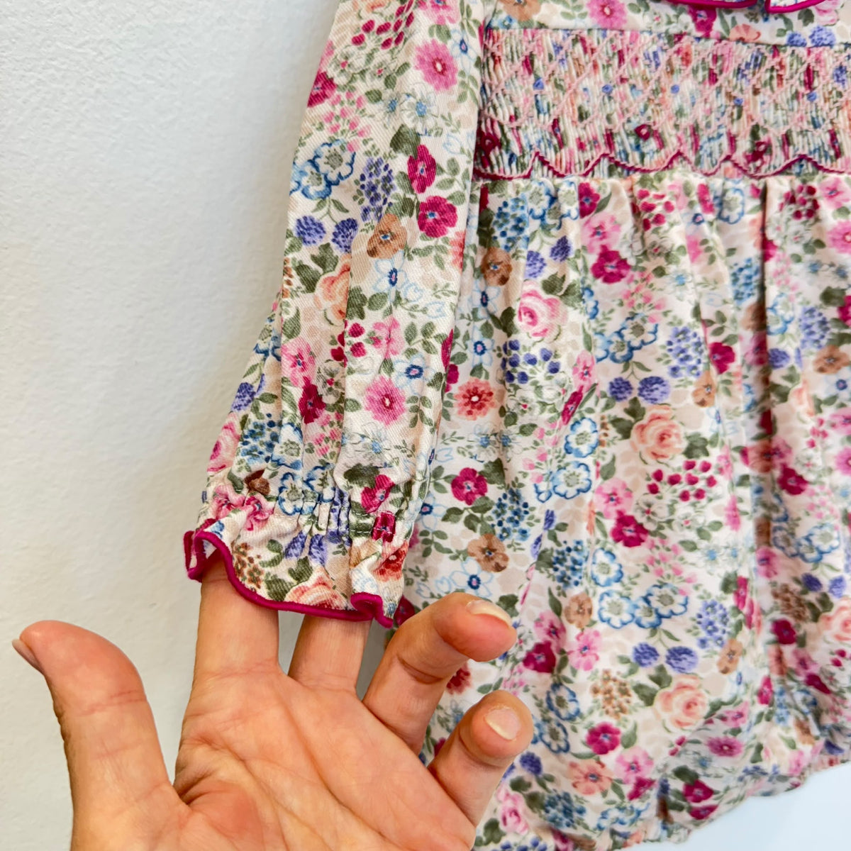 Pagliaccetto bimba floreale in cotone con punto smock e colletto a volant fucsia.