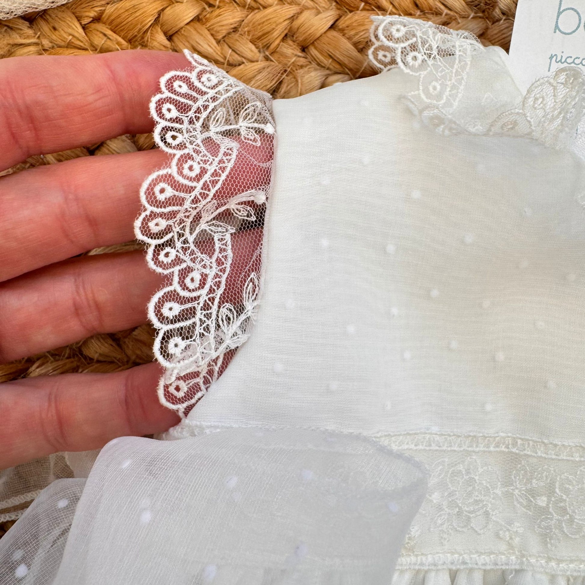 
dettaglio gonna abito battesimo bimba con ricamo floreale e bordo in pizzo