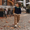 Bambino con maglia a righe beige e pantalone chiaro, outfit autunnale