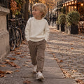 Bambino con maglione blu e marrone e pantalone marrone