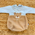 Dettaglio del tessuto teddy e dei bottoni del pagliaccetto neonato azzurro in caldo cotone.