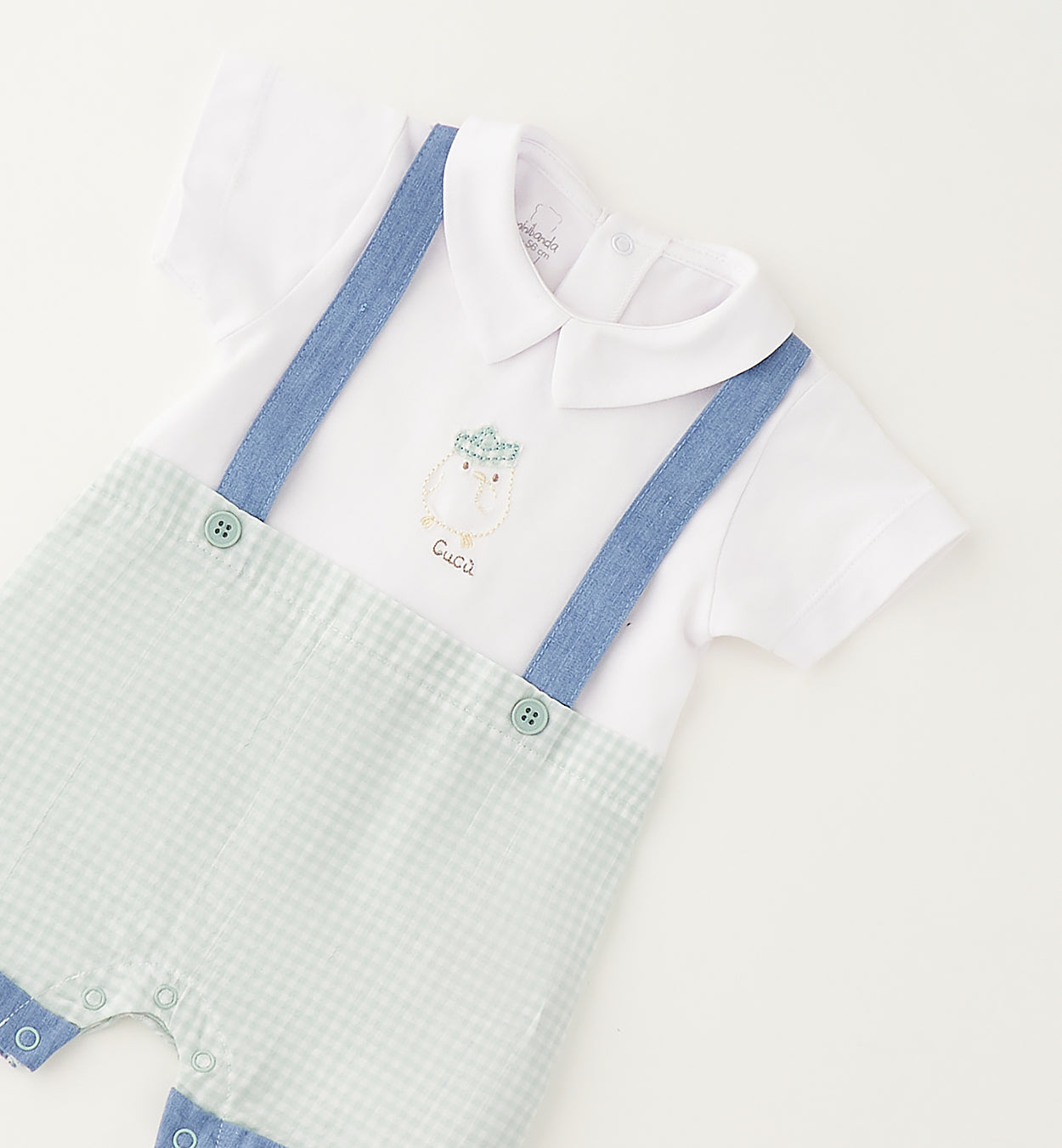 Dettaglio pagliaccetto neonato con colletto classico, ricamo frontale e bretelle azzurre