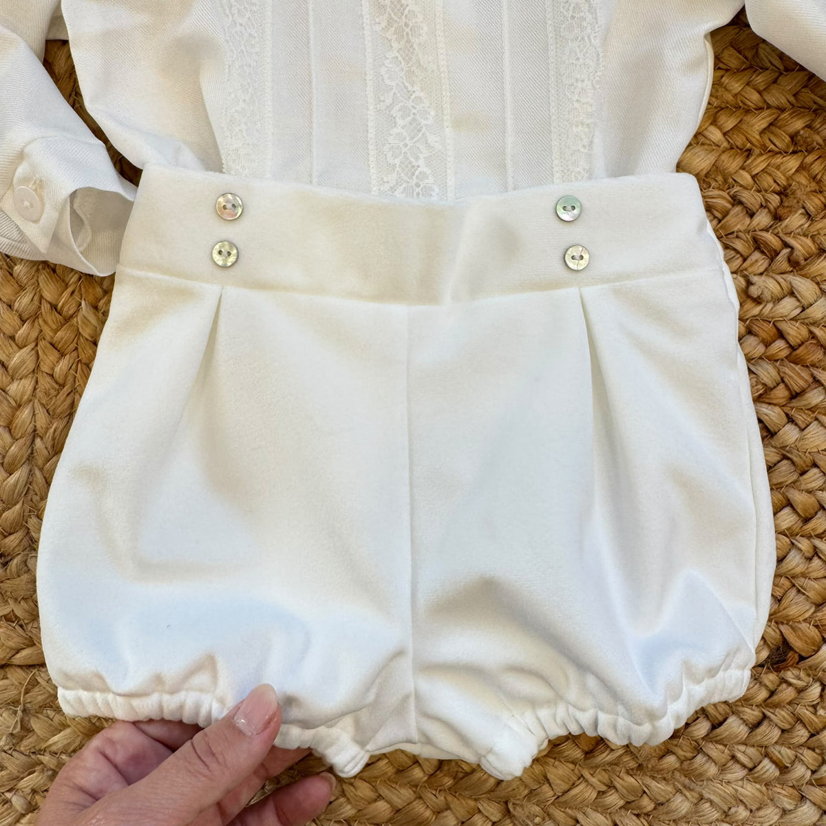 Completo battesimo neonato bianco con camicia a maniche lunghe decorata in pizzo floreale, papillon e pantaloncino a palloncino.