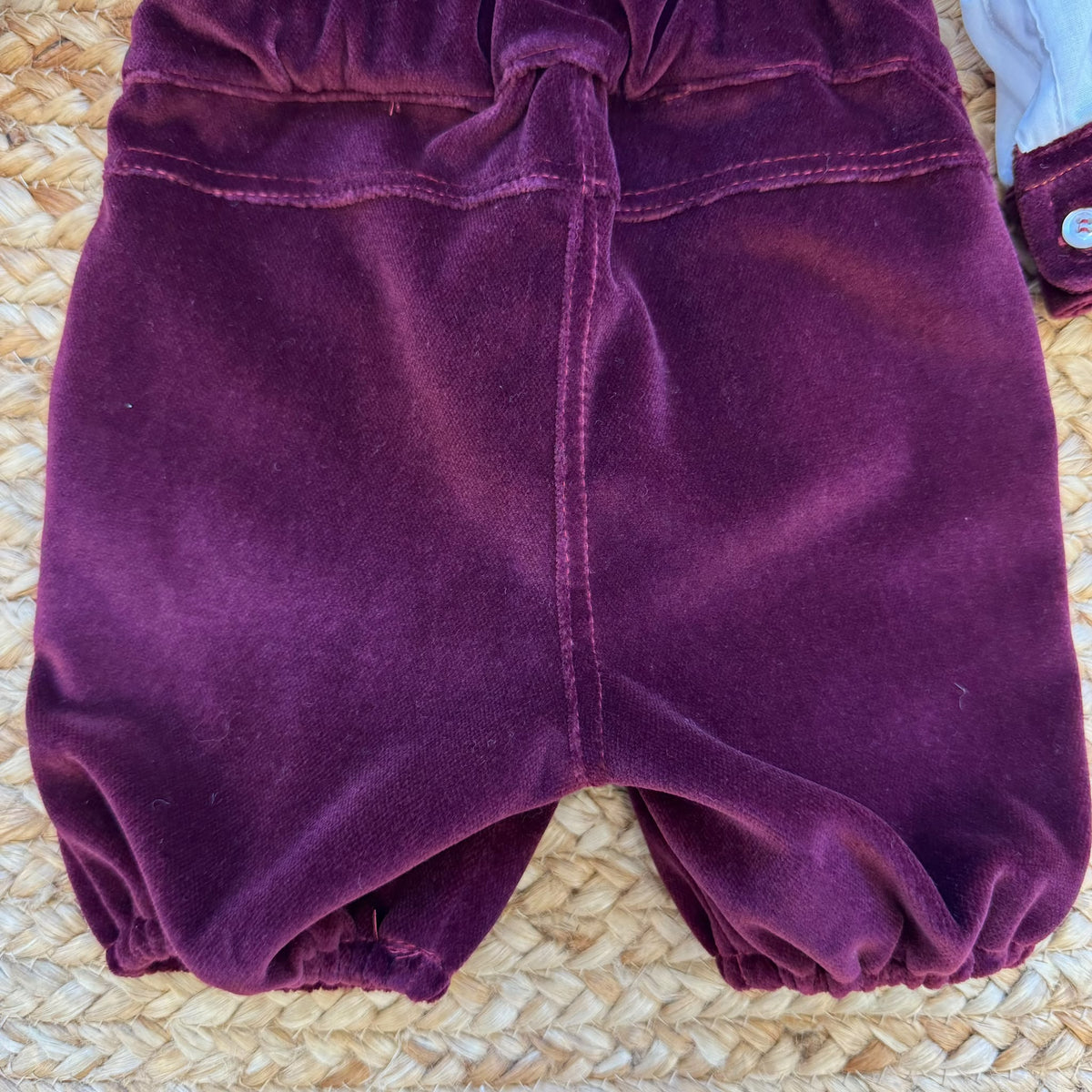 Retro completo battesimo bimbo con bretelle incrociate e fiocco in velluto bordeaux su camicia bianca.