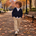 Bambino con maglia polo a righe blu e beige e pantalone blu