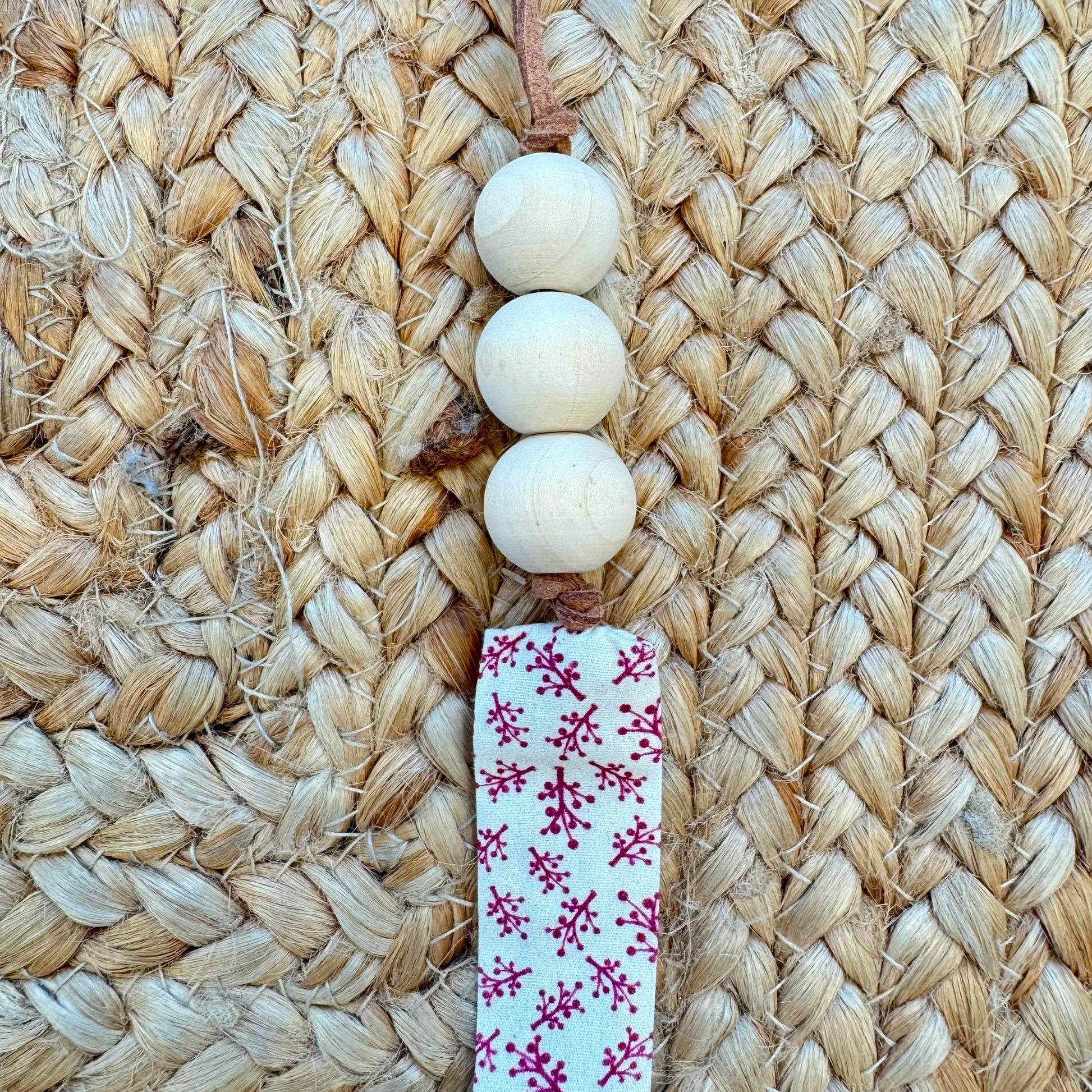Porta ciuccio neonata in tessuto fantasia floreale con perline in legno naturale e clip in metallo.