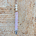 Porta ciuccio neonata in tessuto fantasia floreale con perline in legno naturale e clip in metallo.