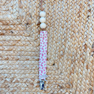 Porta ciuccio neonata in tessuto fantasia floreale con perline in legno naturale e clip in metallo.