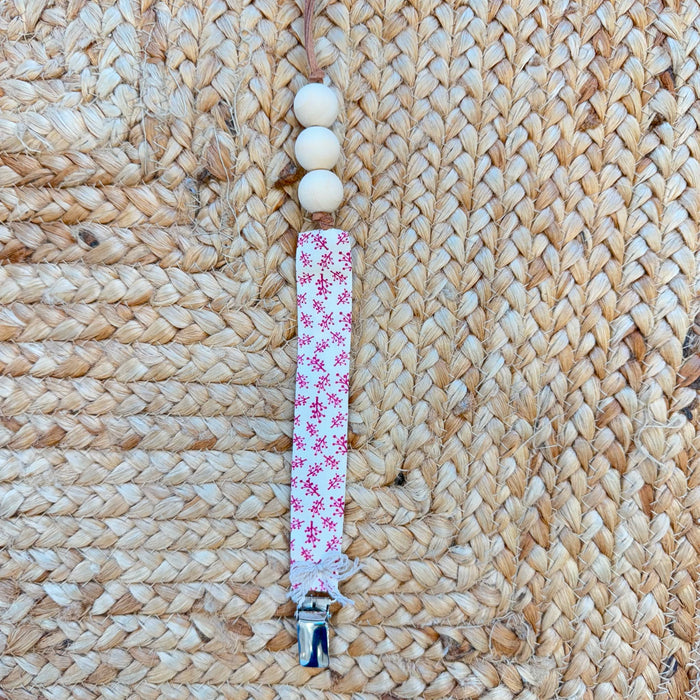 Porta ciuccio neonata in tessuto fantasia floreale con perline in legno naturale e clip in metallo.